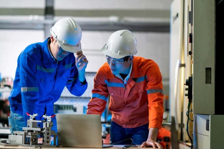 Ingénieur en maintenance industrielle analysant des données sur un ordinateur portable dans une usine.