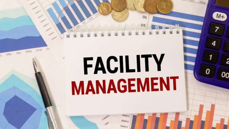 Bloc-notes affichant le texte “Facility Management” posé sur des graphiques financiers, symbolisant la gestion et la performance des services externalisés.